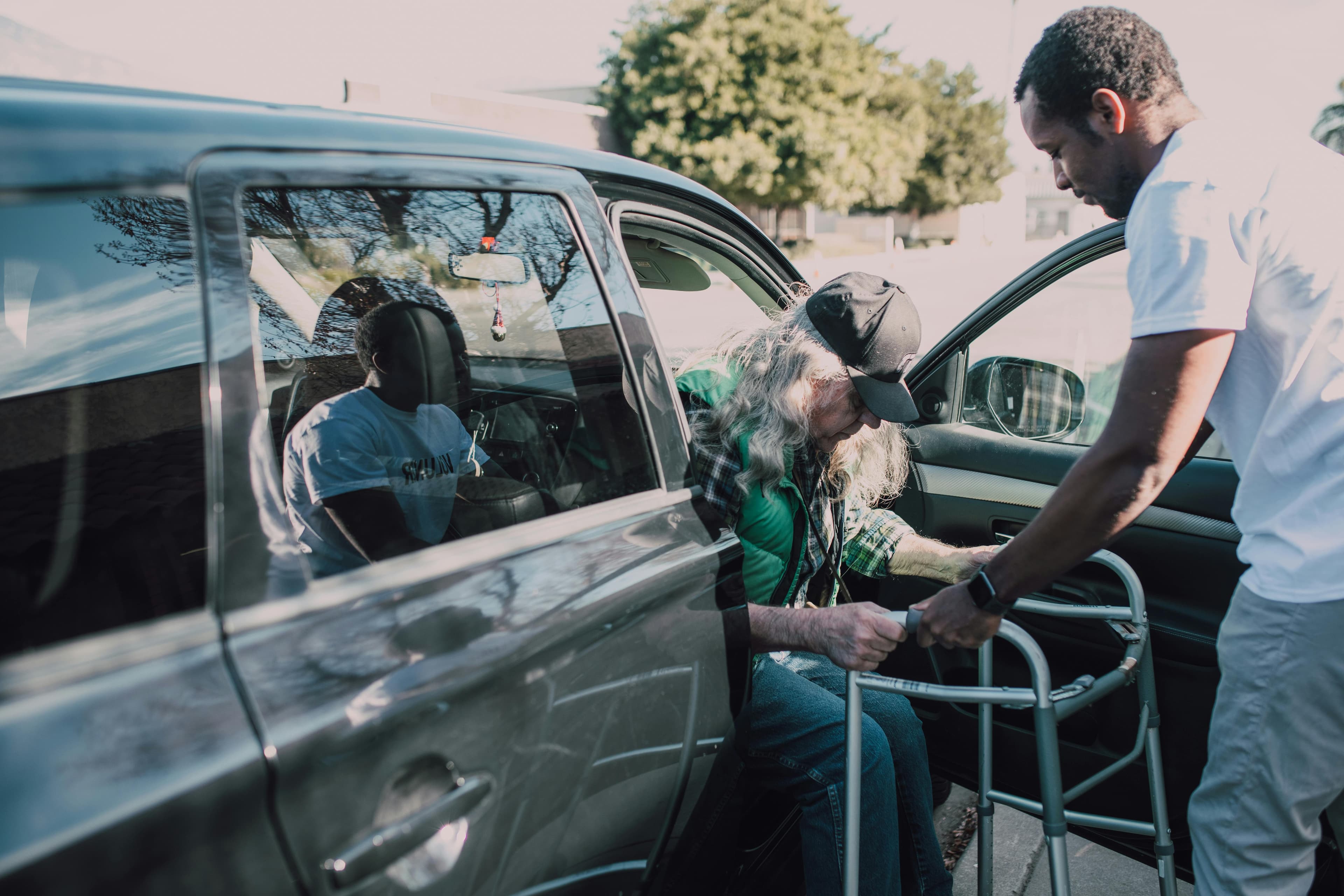 Caregiver helping autistic person get into car for safe transportation